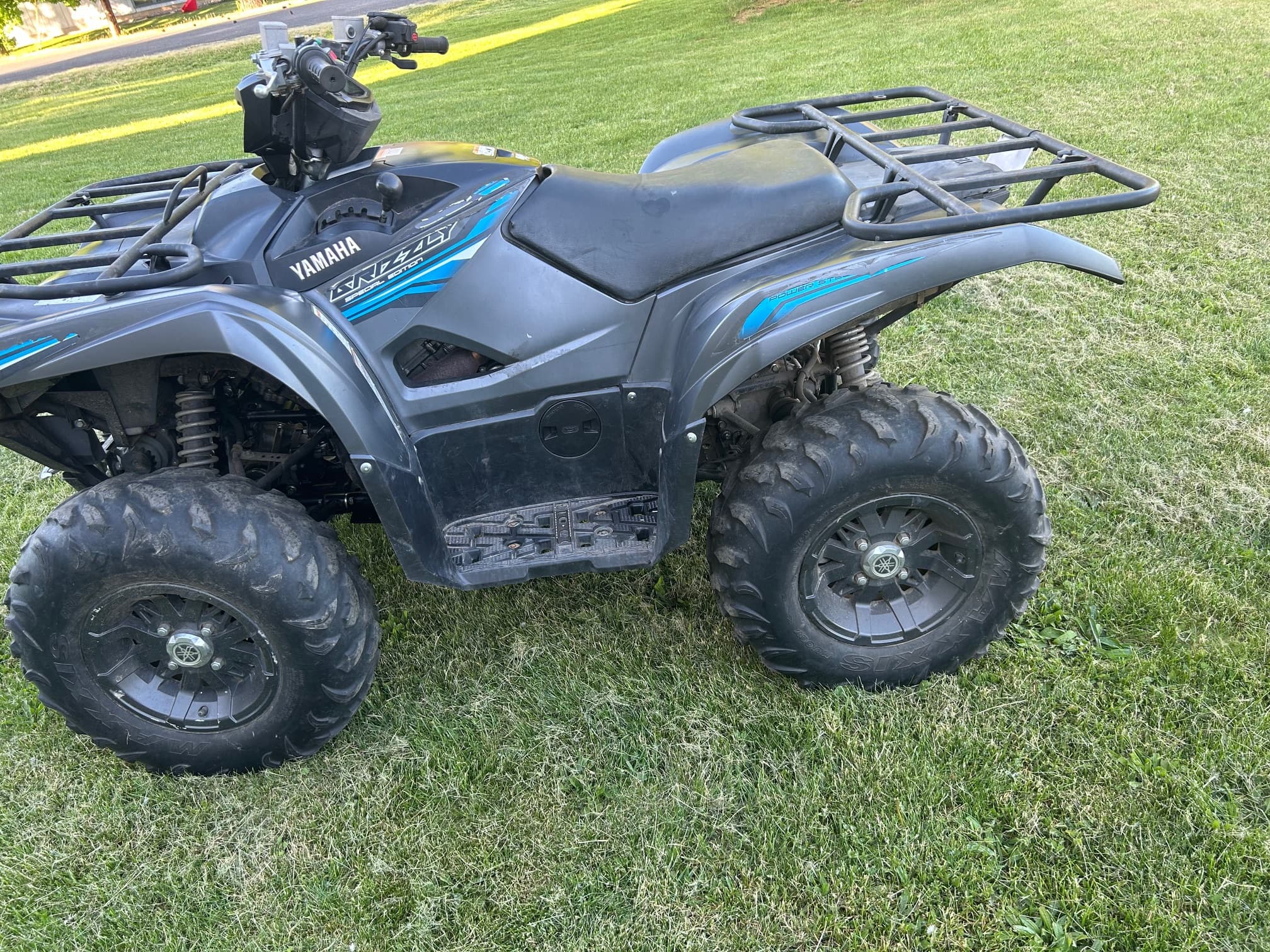 Grey Yamaha Grizzly Special Edition ATV with large tires parked on a green lawn.